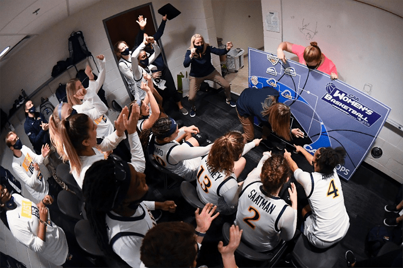Coach Mallon and the team celebrating in the Drexel locker room after the JMU win. Drexel’s athletic trainer Kerri DiPietro is validating the win by placing the Dragon logo in the CAA finals!
