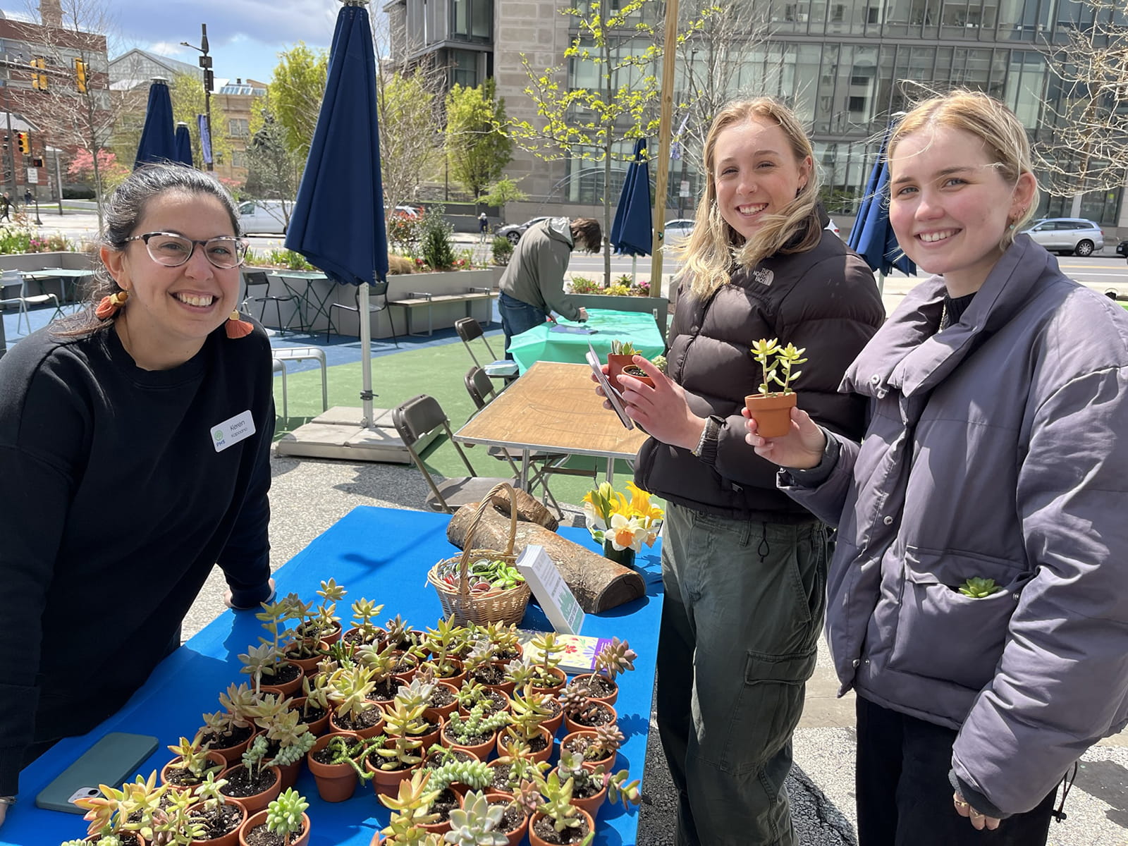Three women stand near a table of succulents.