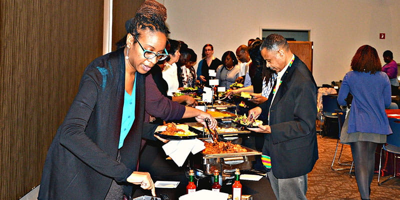 People filling plates up at a buffet table.