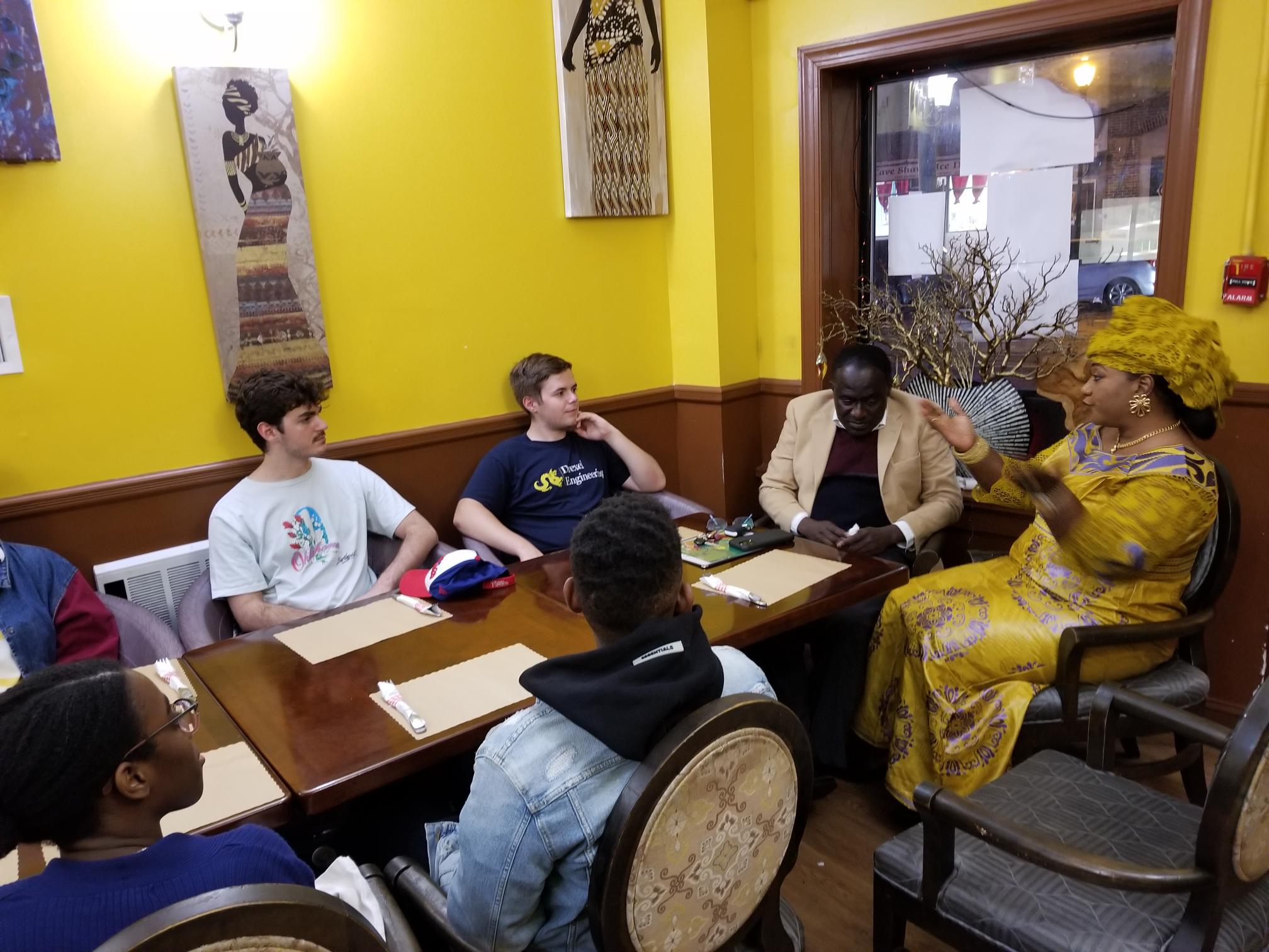 Students listening to Senegalese entrepreneur and West Philadelphia resident Youma Bah at her restaurant.