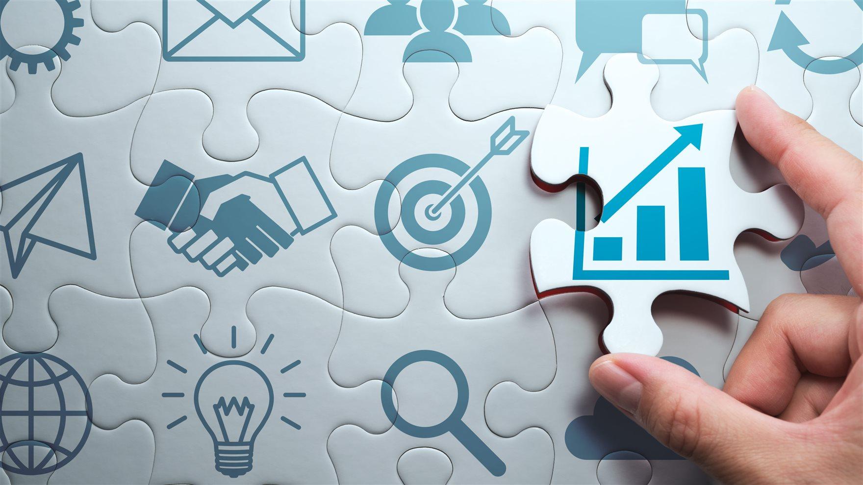 Image of a hand putting a puzle piece showing a map of growth in a puzzle with other iconography related to career success, like an email and a lightbulb and a handshake and a magnifying glass.