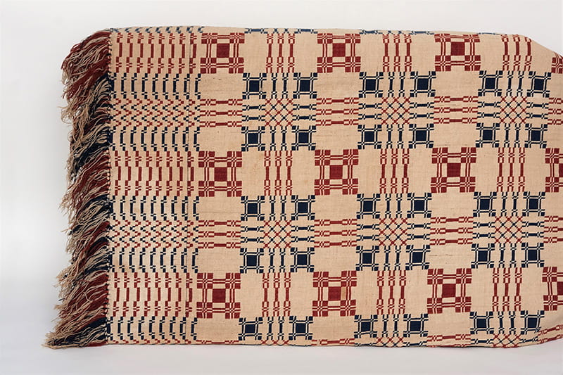 Double woven coverlet. Cream with red and dark blue design, red and dark blue with blocks of plain weave in red and blue. Given to Passmore Williamson while in prison for rescuing Jane Johnson and her children.