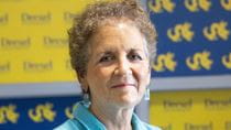 Marla Gold stands with her arms crossed in front of Drexel logos.