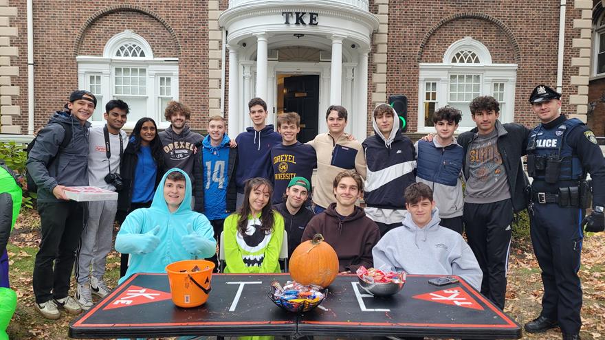 Police Officer Sean McCallion poses with Drexel fraternity and sorority members at their Halloween community event