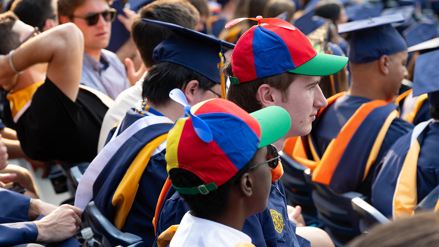 Two men wearing colorful pinwheel caps.